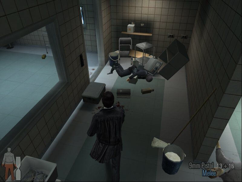 A screenshot from Max Payne 2 showing Max standing in a hospital having shot an enemy sho is lying in a heap amid boxes.